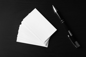 Blank business cards with pen on dark background