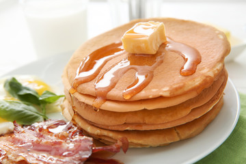 Plate with tasty pancakes and bacon on table, closeup