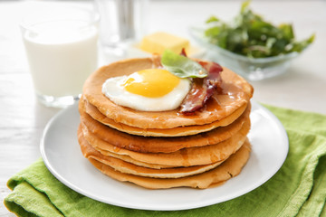 Plate with tasty pancakes, fried egg and bacon on table