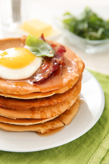 Plate with tasty pancakes, fried egg and bacon on table