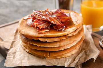 Tasty pancakes with bacon on parchment paper