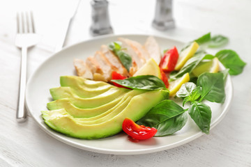 Plate with tasty grilled chicken fillet and vegetables on white wooden table