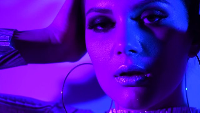 Beauty sexy girl in colorful bright neon lights posing in studio. High fashion model woman, trendy glowing makeup. Night club, party. Slow motion. 3840X2160 4K UHD video footage