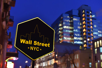 sign board of Wall Street in NYC on background business center in the night
