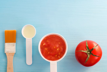 Plastic scoops with tomato puree and olive oil. Ingredients for preparing homemade facial mask. DIY cosmetics recipe. Top view, copy space.