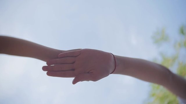 Successful team: many hands holding together on sky background in slowmotion.