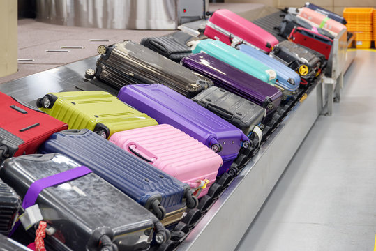 Bright Suitcases On Luggage Conveyor Belt In Airport