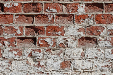Old red-white brick wall with peeling plaster as background, texture