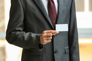 Man with business card on blurred background, closeup