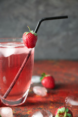 Glass of tasty strawberry lemonade on table
