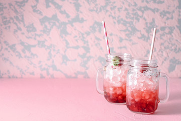 Mason jars with tasty strawberry lemonade on table