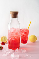 Bottle and glass with tasty strawberry lemonade on table