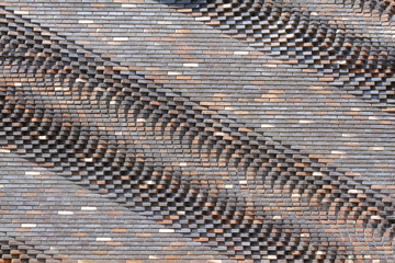 Colorful (grey, beige, black, orange and brown) relief brick wall as background, texture