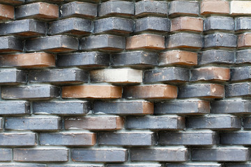 Colorful (grey, beige, black, orange and brown) relief brick wall as background, texture