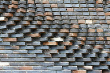 Colorful (grey, beige, black, orange and brown) relief brick wall as background, texture