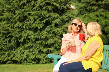 Beautiful mature women resting on bench in park