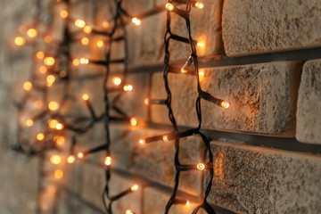 Beautiful bright Christmas garland near brick wall, closeup