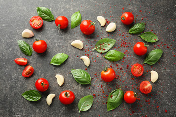Composition with fresh cherry tomatoes, basil and garlic on grey background