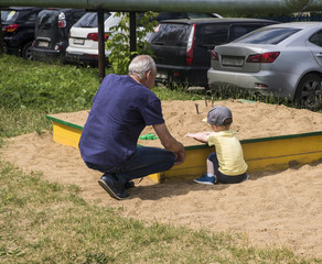 A man is playing with a child in a sandbox