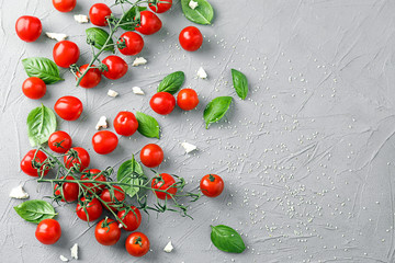 Fresh cherry tomatoes with basil on textured background