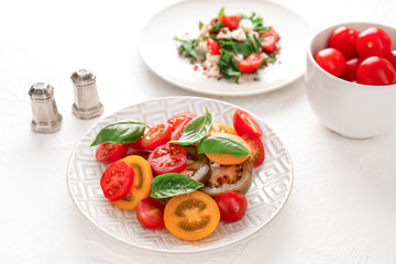 Different sliced tomatoes with basil on plate
