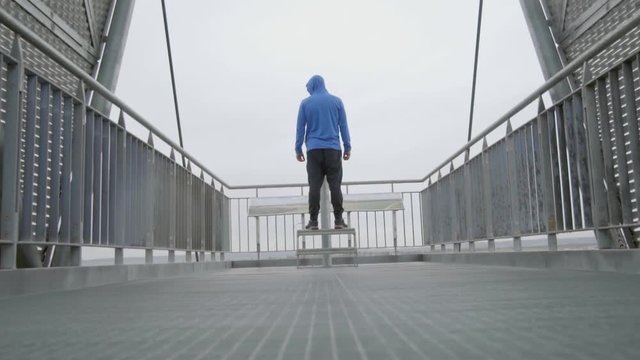 A man is overlooking a city in the rain. He is standing on a platform. It is raining. This epic shot can be used for example a motivational video.