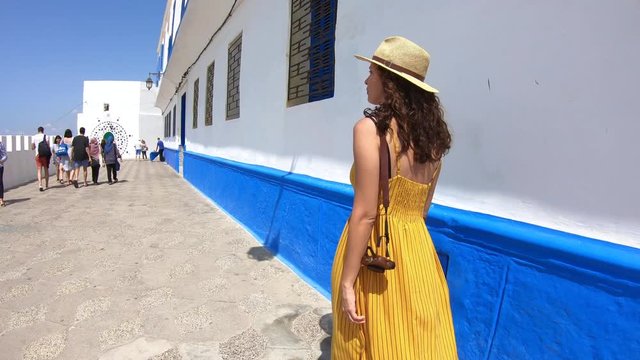 4k Video of a Woman with yellow dress and hat walking in a street of a village in Morocco