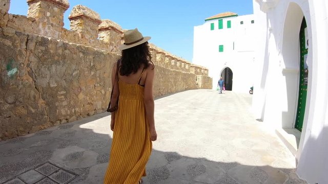 4k Video of a Woman with yellow dress and hat walking in a street of a village in Morocco