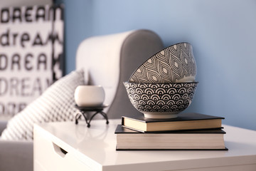 Commode with books and bowls in interior of living room