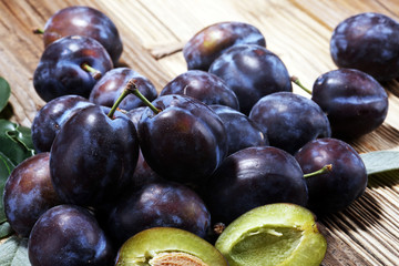 Plums on rustic background. Half of blue plum fruit. Many beautiful plums with leaves