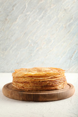 Stack of delicious thin pancakes on wooden board