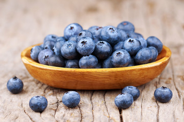 Blueberries in a wood bowl on a wooden table, Healthy eating and nutrition concept