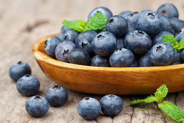 Blueberries in a wood bowl on a wooden table, Healthy eating and nutrition concept