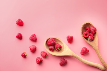 Wooden spoons with ripe aromatic raspberries on color background