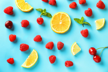 Composition with ripe aromatic raspberries, lemon slices and cherries on color background