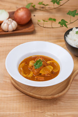 Tasty dinner with chicken curry in bowl on wooden background