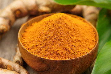 Turmeric powder in wooden bowls on wooden table