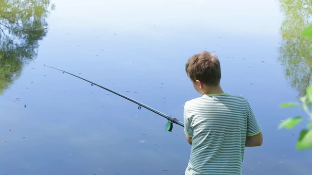 Young kid fishing on river in scenic place. Happy family on summer vacation in countryside concept. Real time full hd video footage.