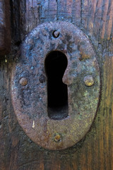 Close-up of a rusty metallic keyhole of a worn wood door. No people.