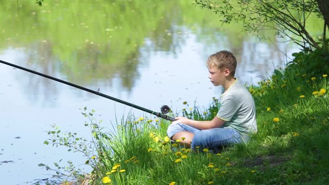 Young kid fishing alone on river in scenic place during summer vacation in countryside. Real time full hd video footage.