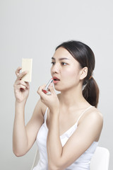 caucasian woman applying lipstick in mirror
