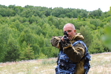 Hunting season. A man of 35-40 years old hunters aiming from a firearm in a clearing in the forest.