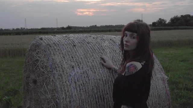 beautifull and alternative inked girl posing big bale of hay