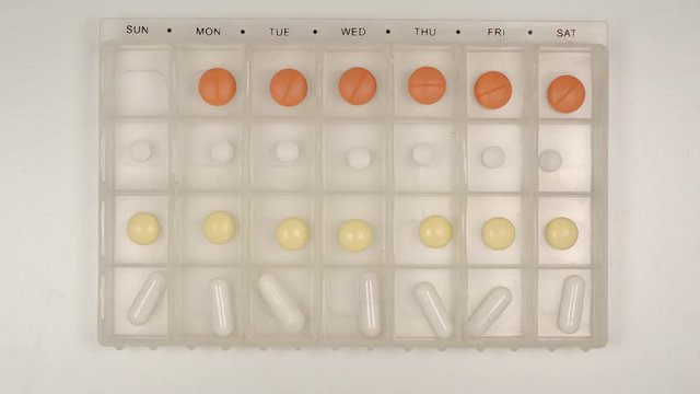 TOP VIEW: Female hand takes a pill from a pill organizer