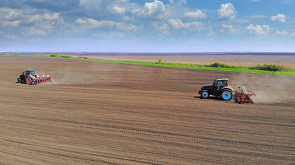 Farmers in two tractors seeding, sowing agricultural crops at field