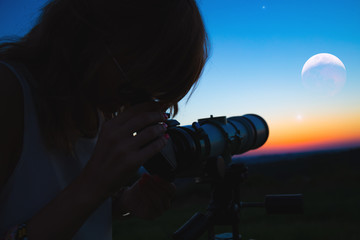 Girl looking at lunar eclipse through a telescope. My astronomy work.