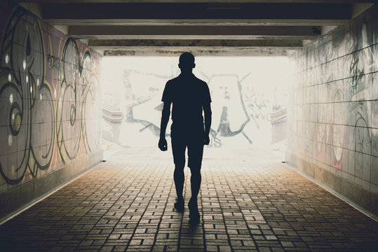 silhouette of a man walking on an underground pedestrian crossing