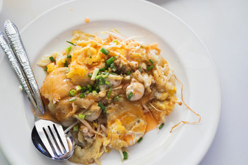 Oyster Omelette with Chili Sauce on white dish in local restaurant in Bangkok.