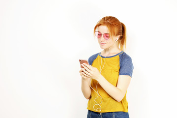 Young attractive natural redhead woman smiling, enjoying favorite song with hands free earphones....