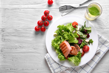 Plate with tasty grilled fish and fresh salad on table
